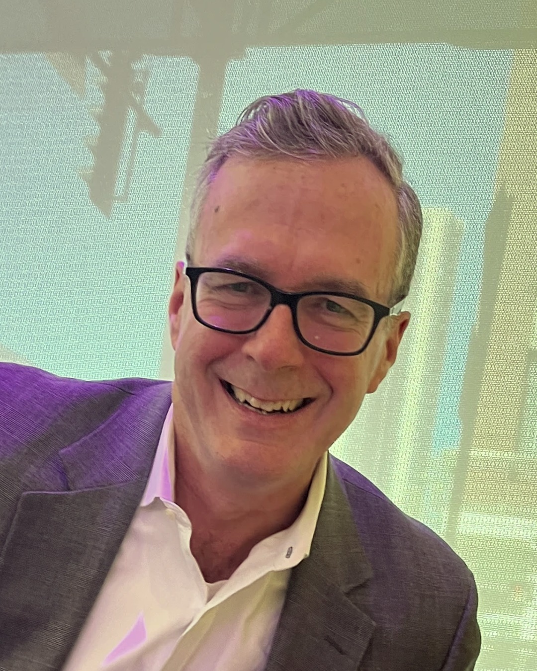 Bruce Stebbins, consultant, smiling in a grey blazer